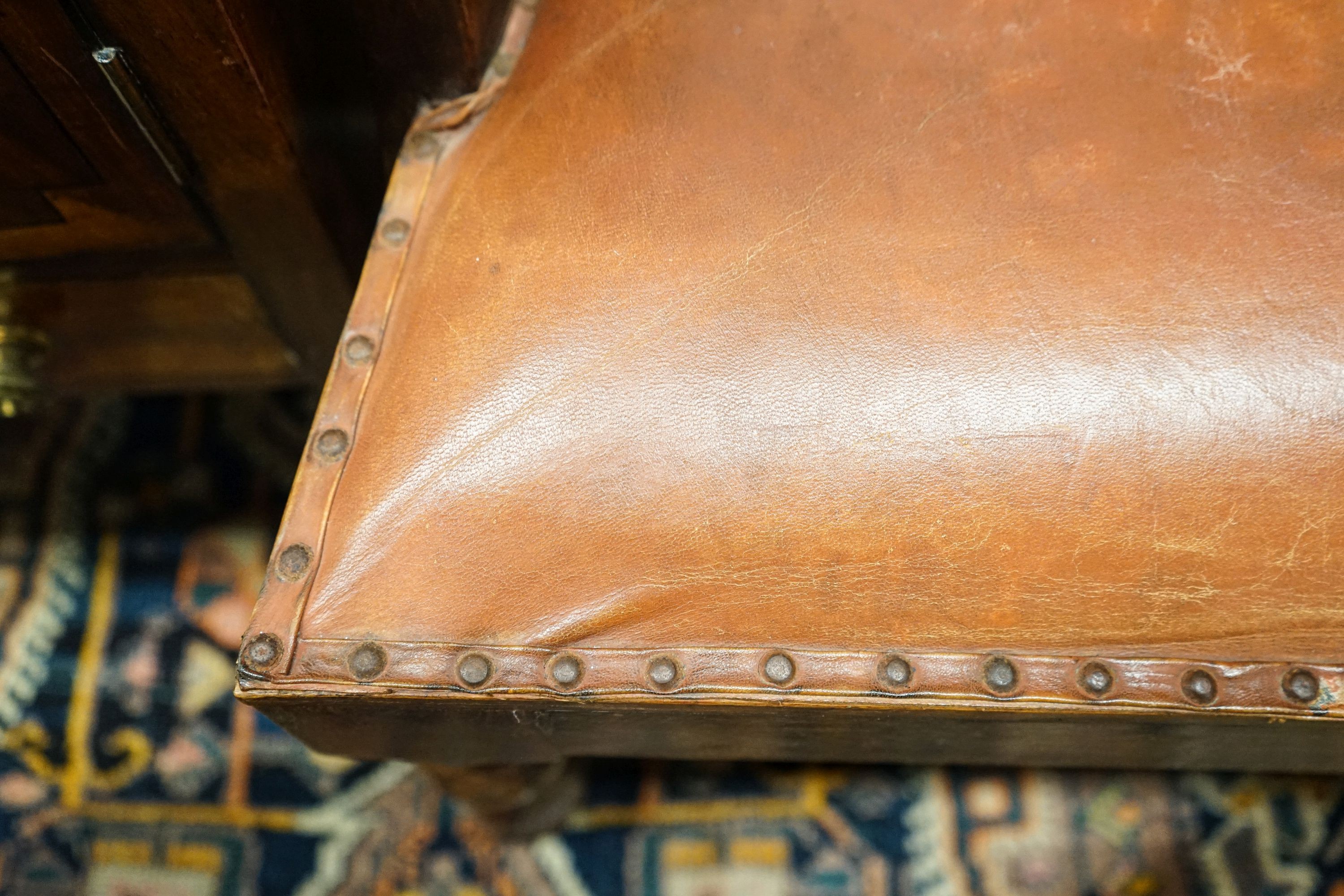 A pair of Victorian style hardwood elbow chairs with faded red leather upholstery, width 55cm, depth 45cm, height 92cm